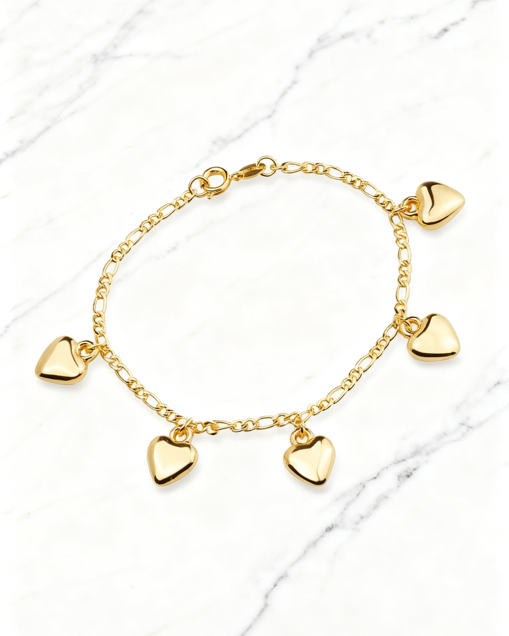 Pulseira Dourada com Pingentes de Coração Auvane em fundo de mármore claro com veios elegantes
