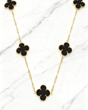 Colar Dourado 5 Trevos Preto Auvane em fundo de mármore claro com veios elegantes