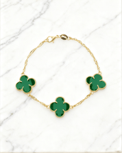 Pulseira Dourada Trevos com Zircônia Verde Auvane em fundo de mármore claro com veios elegantes