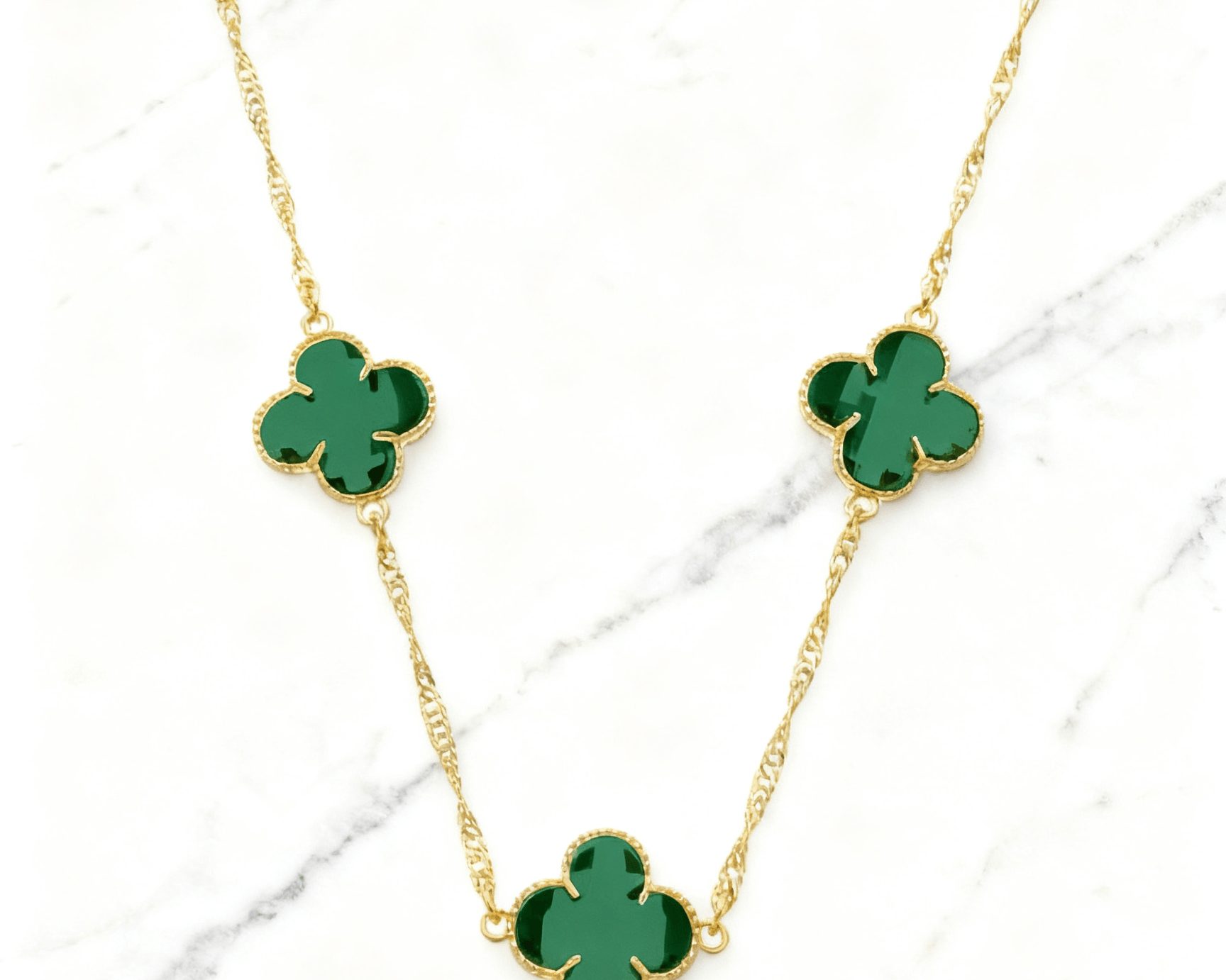 Colar Dourado 5 Trevos Verde Auvane em fundo de mármore claro com veios elegantes