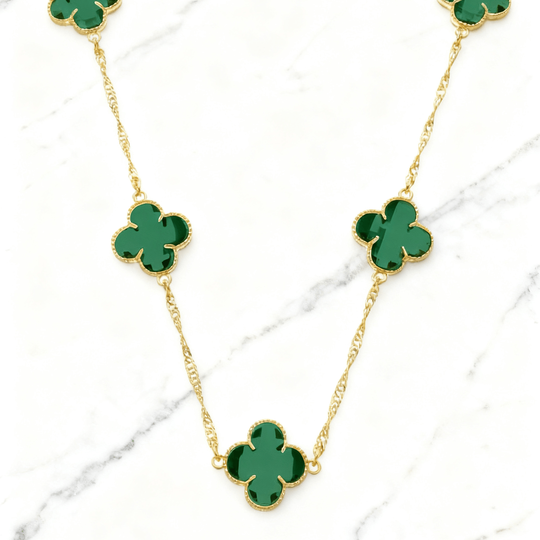Colar Dourado 5 Trevos Verde Auvane em fundo de mármore claro com veios elegantes
