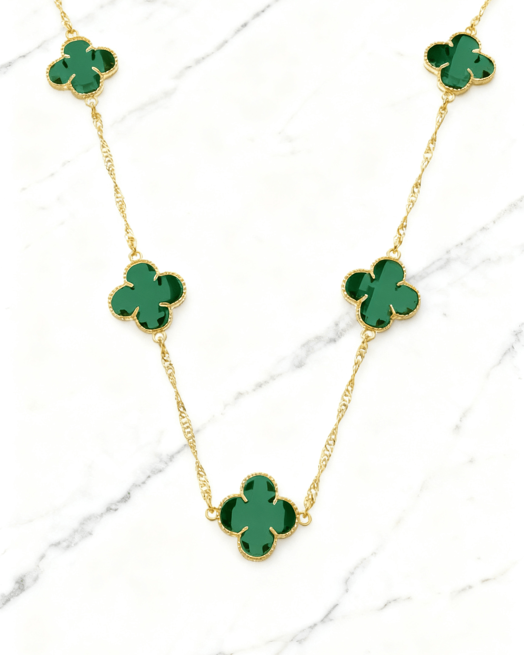 Colar Dourado 5 Trevos Verde Auvane em fundo de mármore claro com veios elegantes