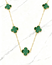 Colar Dourado 5 Trevos Verde Auvane em fundo de mármore claro com veios elegantes