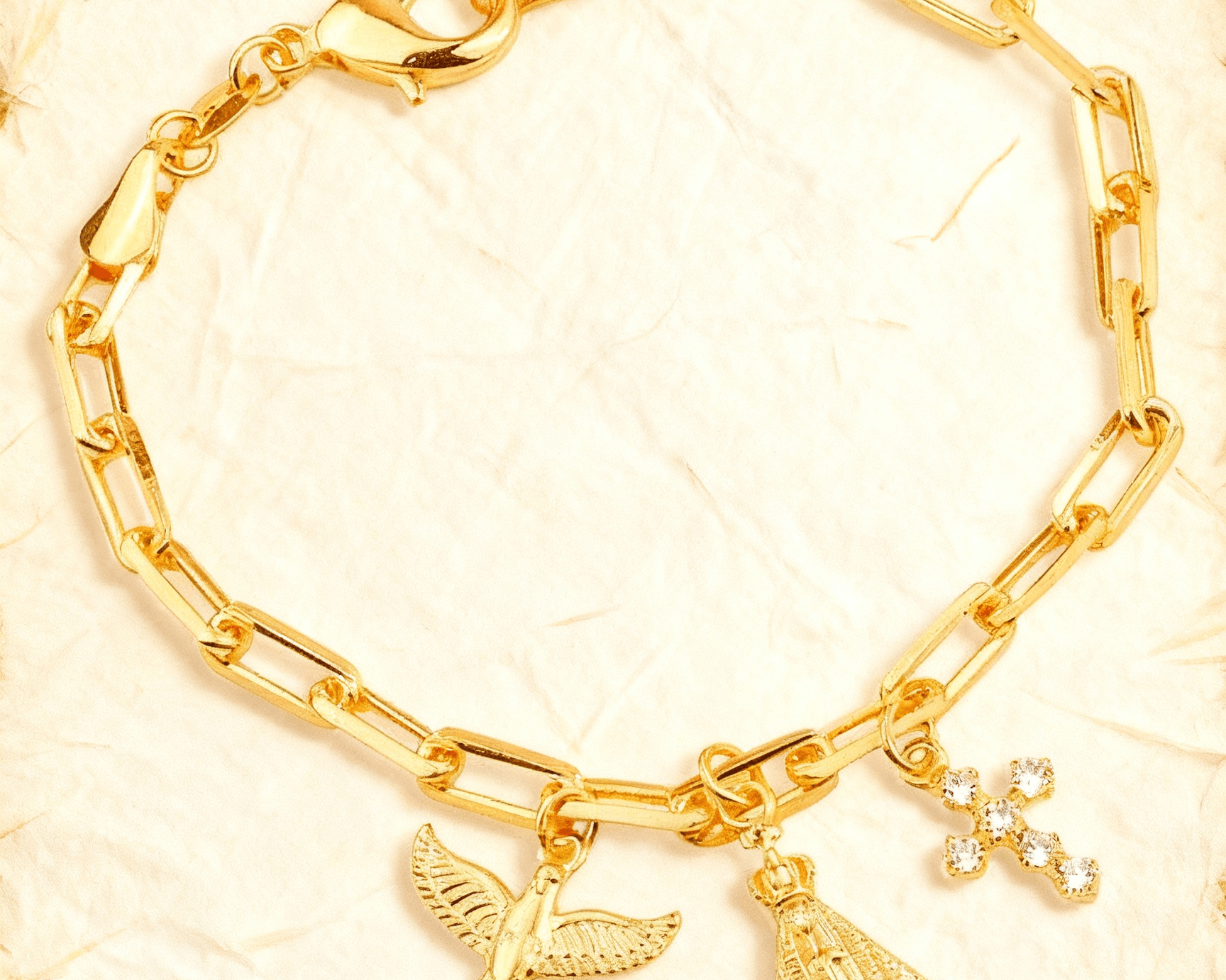Pulseira Dourada Religiosa Nossa Senhora, Espírito Santo e Cruz Auvane sobre papel artesanal cream