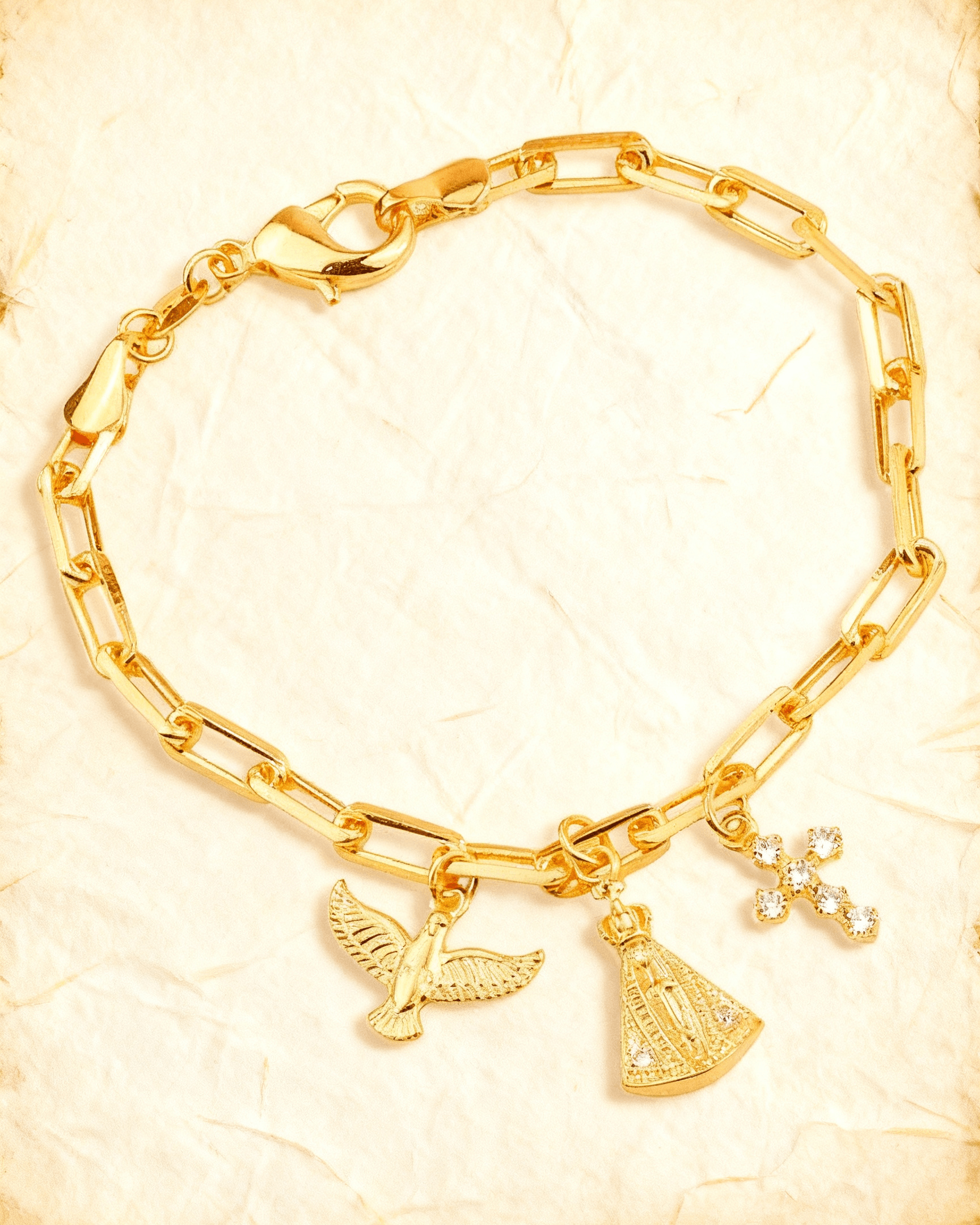 Pulseira Dourada Religiosa Nossa Senhora, Espírito Santo e Cruz Auvane sobre papel artesanal cream