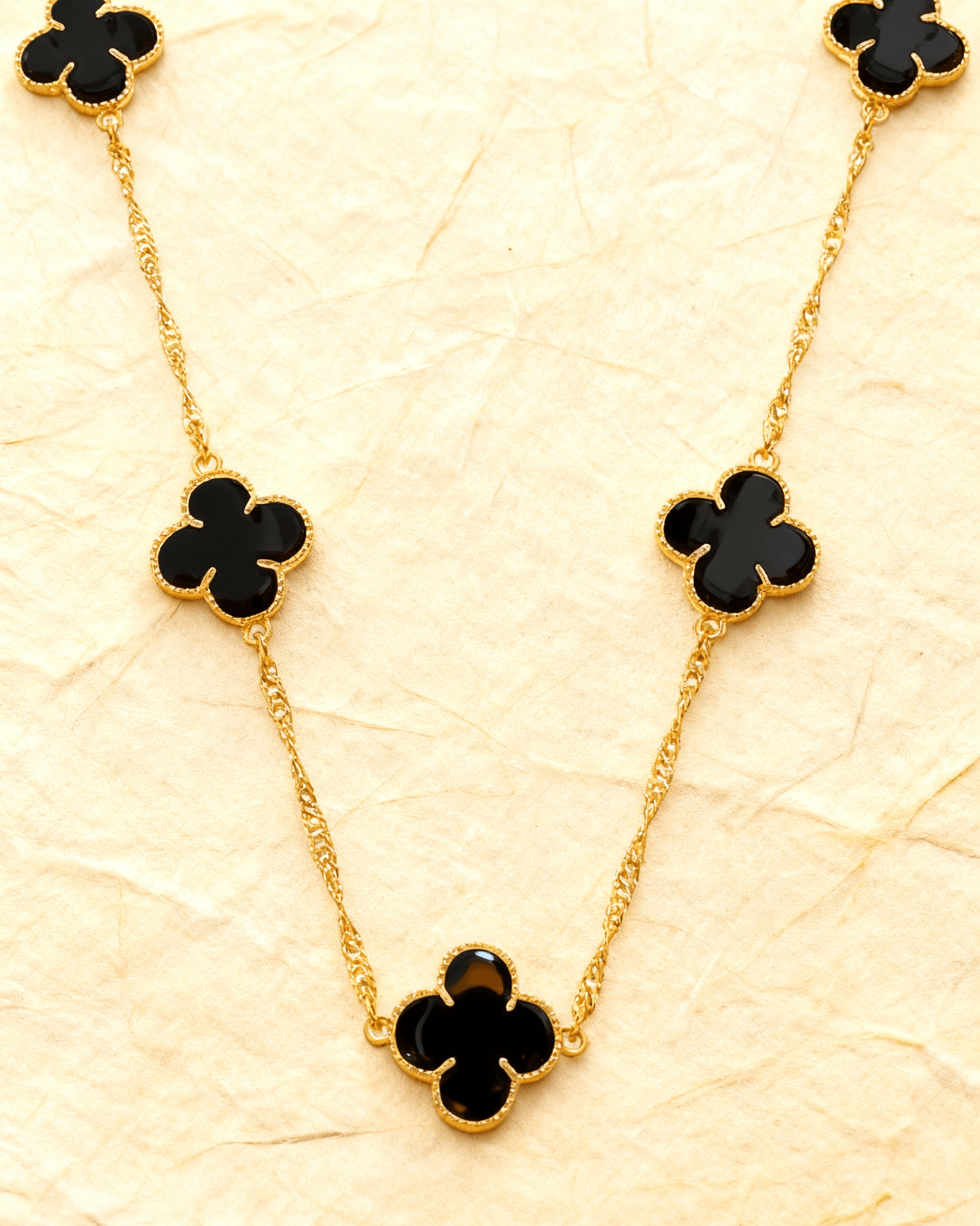 Colar Dourado 5 Trevos Preto Auvane sobre papel artesanal cream