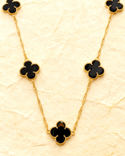 Colar Dourado 5 Trevos Preto Auvane sobre papel artesanal cream