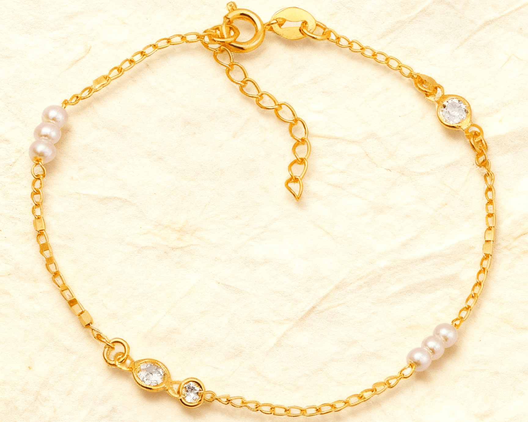 Pulseira Dourada de Pérolas com Ponto de Luz Auvane sobre papel artesanal cream