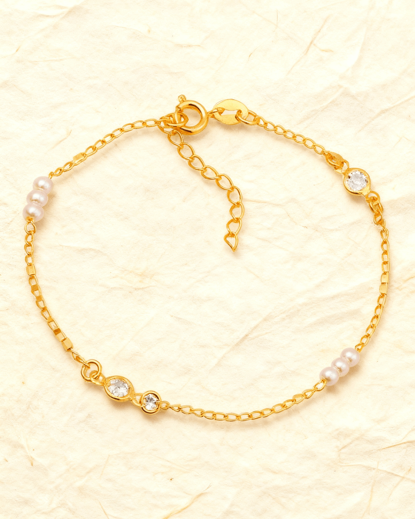 Pulseira Dourada de Pérolas com Ponto de Luz Auvane sobre papel artesanal cream