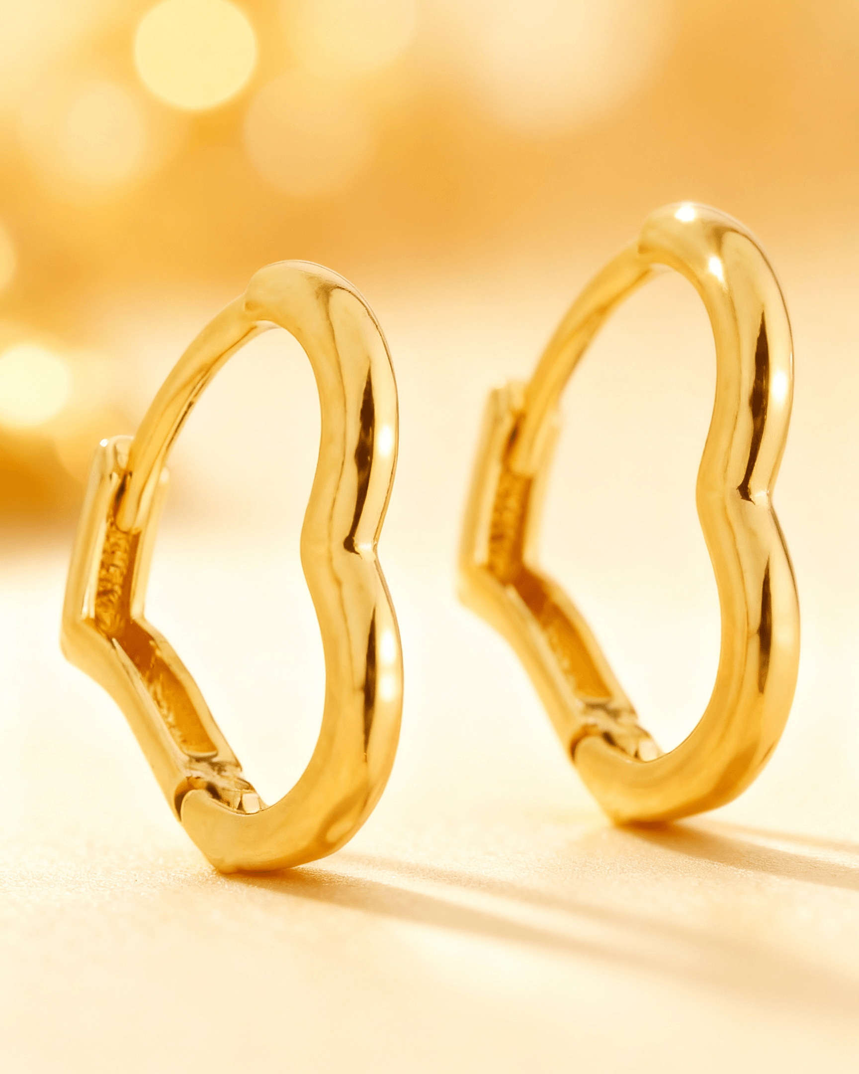 Detalhe macro do Brinco Argolinha Dourada em Formato de Coração Auvane com brilho do dourado